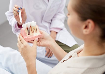 a patient holding a model of dental implants