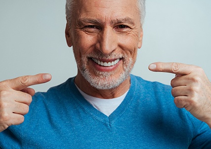 Happy older man pointing at his teeth